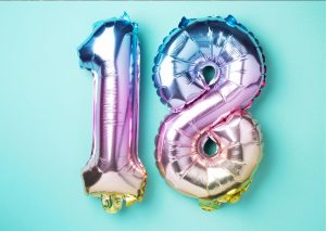 Auf dieser Einladungskarte sehen Sie die Luftballonzahlen 18 in schillernden Farben.